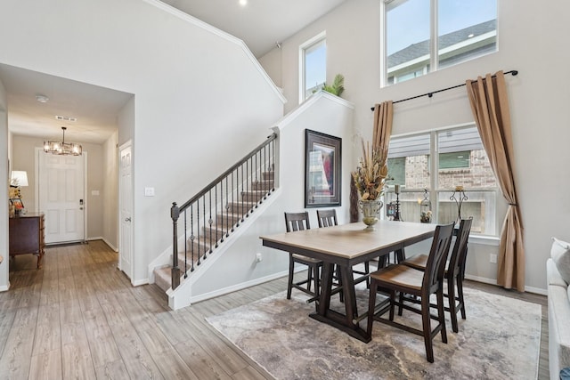 10126 Bayou Oaks Dr, Conroe, TX 77385 - dining space featuring stairs, a chandelier, a towering ceiling, and wood finished floors