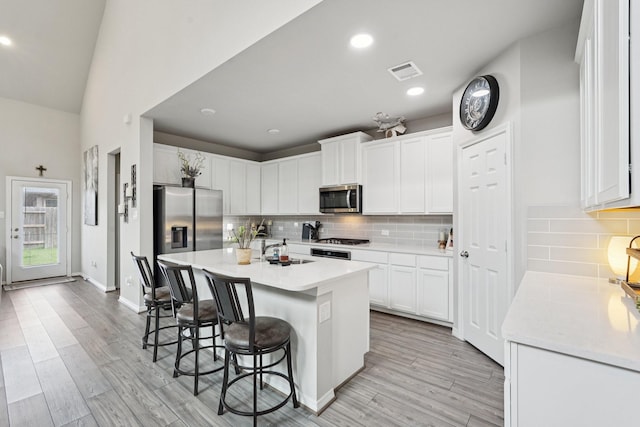 10126 Bayou Oaks Dr, Conroe, TX 77385 - kitchen featuring appliances with stainless steel finishes, a breakfast bar, white cabinets, light countertops, and recessed lighting
