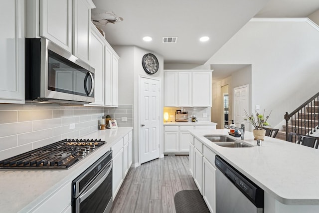 10126 Bayou Oaks Dr, Conroe, TX 77385 - kitchen with appliances with stainless steel finishes, light wood-type flooring, white cabinets, tasteful backsplash, and recessed lighting