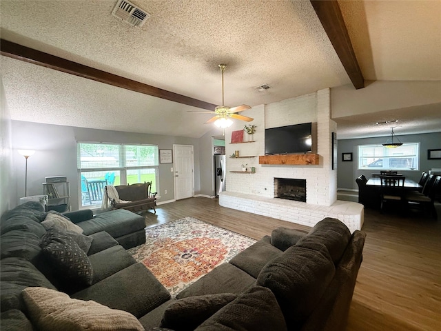 1006 Fairlane Dr, Ganado, TX 77962 - living room with wood finished floors, a textured ceiling, a ceiling fan, a fireplace, and healthy amount of natural light