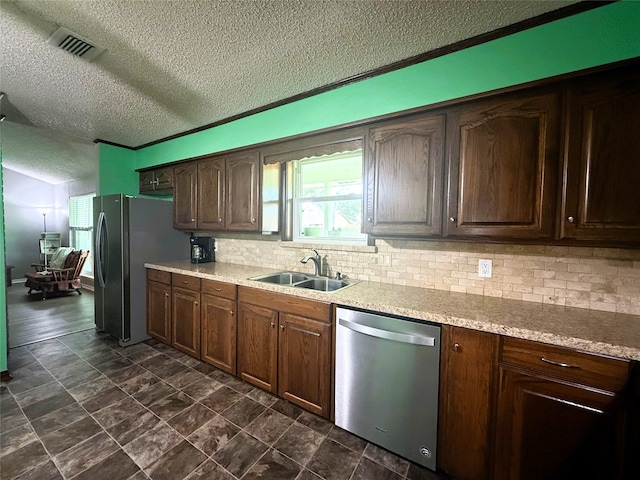 1006 Fairlane Dr, Ganado, TX 77962 - kitchen featuring appliances with stainless steel finishes, a textured ceiling, tasteful backsplash, light countertops, and dark brown cabinets