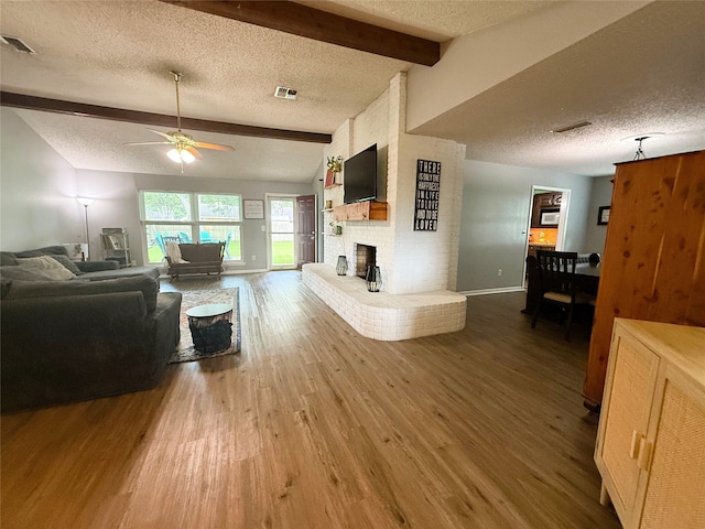 1006 Fairlane Dr, Ganado, TX 77962 - living room with wood finished floors, a textured ceiling, a fireplace, and a ceiling fan