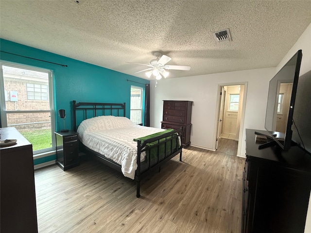 1006 Fairlane Dr, Ganado, TX 77962 - bedroom featuring light wood-style floors, multiple windows, a textured ceiling, and a ceiling fan