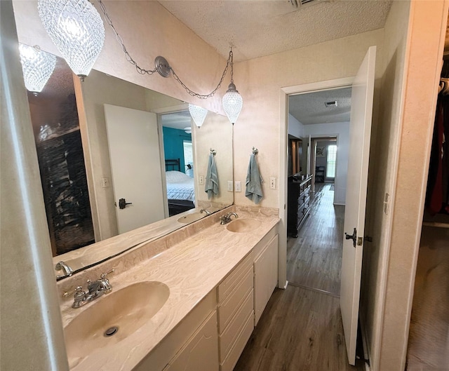 1006 Fairlane Dr, Ganado, TX 77962 - full bathroom featuring connected bathroom, a textured ceiling, double vanity, and wood finished floors