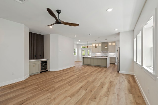 3224 Omega St, Houston, TX 77022 - unfurnished living room with beverage cooler, ceiling fan, recessed lighting, light wood-type flooring, and a bar
