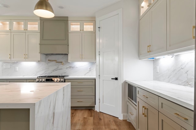 3224 Omega St, Houston, TX 77022 - kitchen featuring decorative backsplash, light wood-style floors, light stone counters, extractor fan, and glass insert cabinets