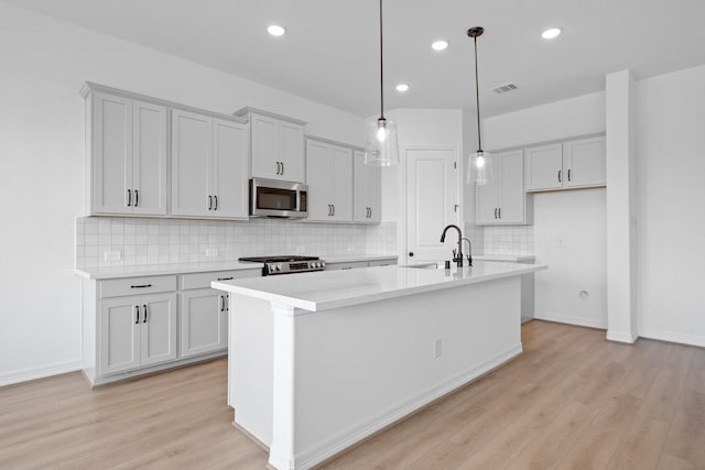 4770 Ara Dr, Richmond, TX 77469 - kitchen with stainless steel appliances, a kitchen island with sink, light wood-style flooring, light countertops, and recessed lighting