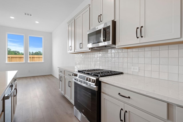 4770 Ara Dr, Richmond, TX 77469 - kitchen with stainless steel appliances, light wood-style flooring, tasteful backsplash, light stone countertops, and recessed lighting