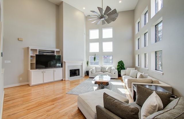 6205 Dell St, Houston, TX 77007 - living room with a towering ceiling, a fireplace with flush hearth, light wood-style floors, ceiling fan, and recessed lighting