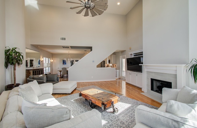 6205 Dell St, Houston, TX 77007 - living area featuring a towering ceiling, light wood-type flooring, a ceiling fan, a premium fireplace, and a chandelier