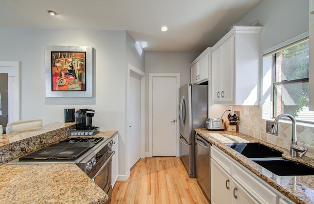 6205 Dell St, Houston, TX 77007 - kitchen with appliances with stainless steel finishes, light wood finished floors, white cabinets, light stone countertops, and tasteful backsplash