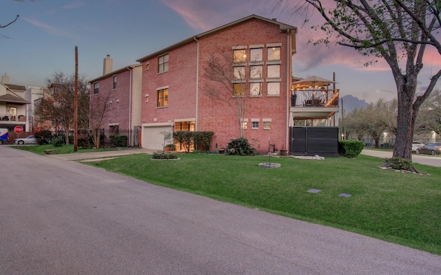 6205 Dell St, Houston, TX 77007 - property exterior at dusk featuring brick siding, a chimney, an attached garage, concrete driveway, and a lawn