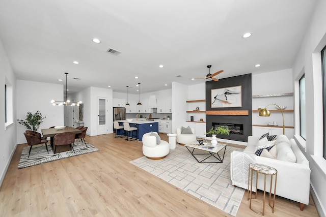 5520 Chapman St, Houston, TX 77009 - living room featuring a fireplace, light wood-style flooring, recessed lighting, a ceiling fan, and a chandelier