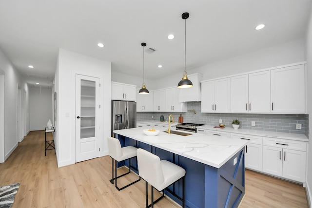 5520 Chapman St, Houston, TX 77009 - kitchen featuring appliances with stainless steel finishes, light wood-style floors, backsplash, white cabinetry, and recessed lighting