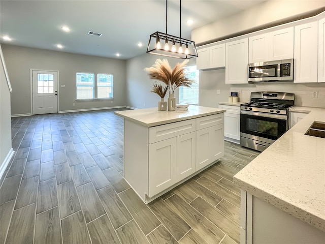 4815 Keeland St, Houston, TX 77016 - kitchen featuring stainless steel appliances, wood tiled floors, recessed lighting, pendant lighting, and white cabinetry