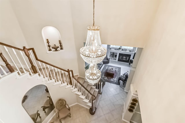 13719 Country Green Ct, Houston, TX 77059 - staircase featuring a chandelier, tile patterned floors, a fireplace, and a towering ceiling