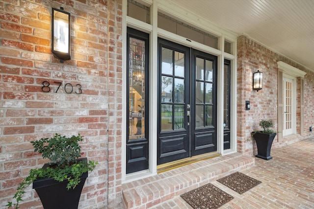 8703 Chelmsford Ln, Spring, TX 77379 - view of exterior entry featuring brick siding, covered porch, and french doors