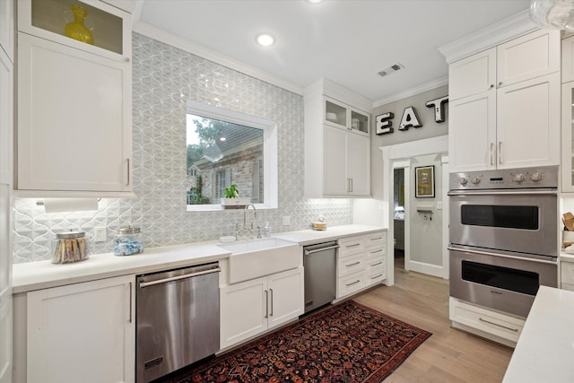 8703 Chelmsford Ln, Spring, TX 77379 - kitchen with stainless steel appliances, ornamental molding, light countertops, decorative backsplash, and white cabinets