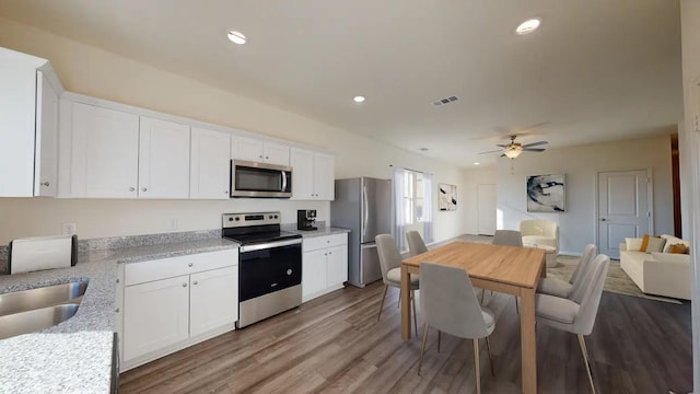 9309 Beryl Ln, Conroe, TX 77303 - kitchen with stainless steel appliances, white cabinetry, a ceiling fan, wood finished floors, and recessed lighting