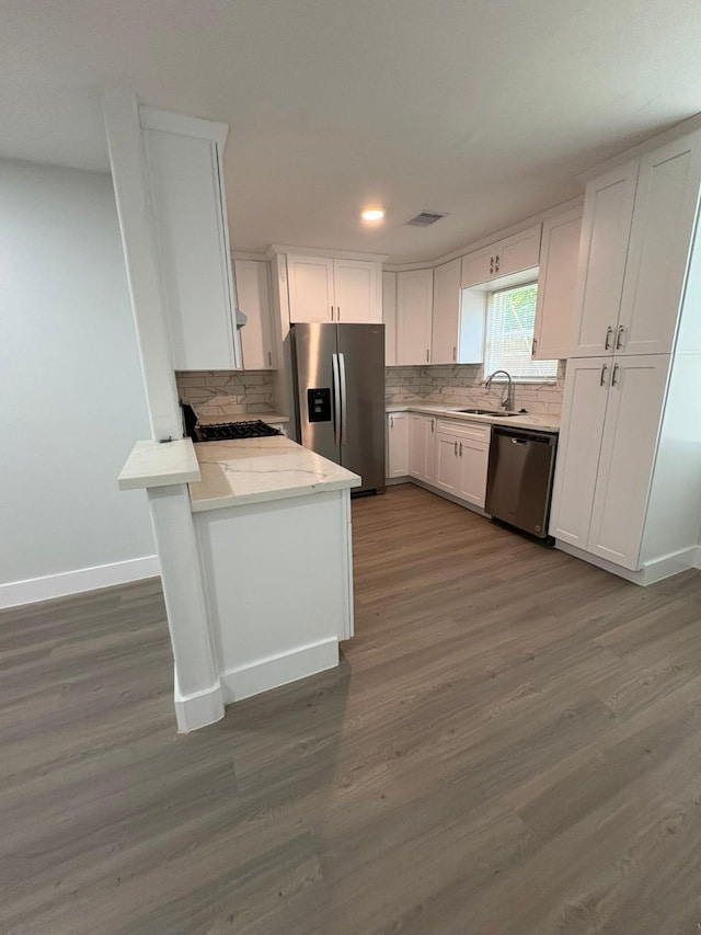 3923 Hickok Ln, Houston, TX 77047 - kitchen with stainless steel appliances, white cabinets, tasteful backsplash, dark wood finished floors, and a peninsula