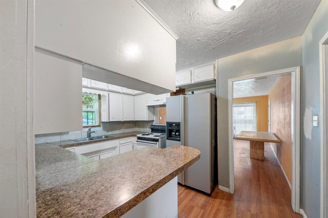 810 W N St, Livingston, TX 77351 - kitchen with refrigerator with ice dispenser, white range with electric stovetop, light wood-style flooring, white cabinets, and a textured ceiling