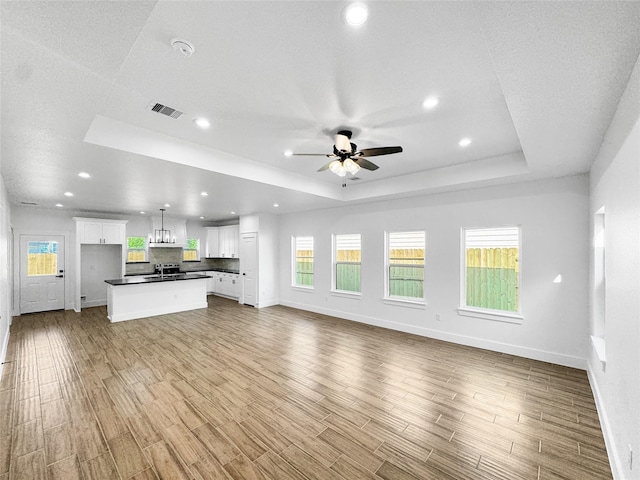 314 E Republic Ave, Baytown, TX 77520 - unfurnished living room with a tray ceiling, ceiling fan, wood finished floors, and recessed lighting