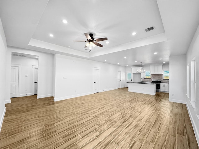 314 E Republic Ave, Baytown, TX 77520 - unfurnished living room with a tray ceiling, a ceiling fan, light wood-style floors, and recessed lighting
