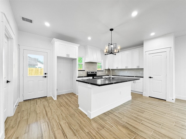 314 E Republic Ave, Baytown, TX 77520 - kitchen with premium range hood, electric stove, a chandelier, dark countertops, and white cabinetry