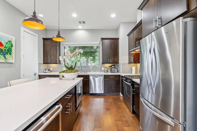 703 Bayou St, Houston, TX 77020 - kitchen featuring stainless steel appliances, light countertops, dark brown cabinets, dark wood finished floors, and recessed lighting