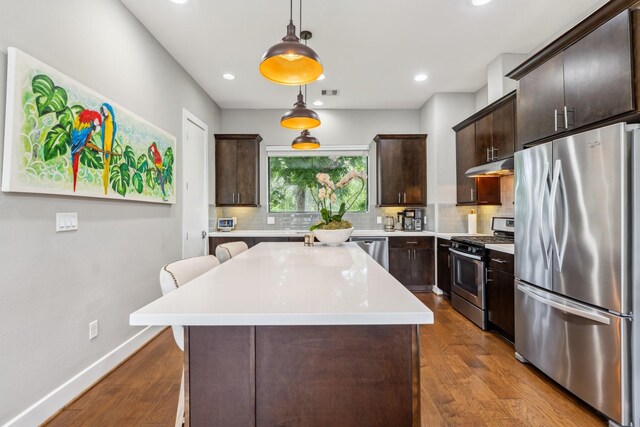 703 Bayou St, Houston, TX 77020 - kitchen with stainless steel appliances, under cabinet range hood, dark brown cabinets, decorative backsplash, and light countertops