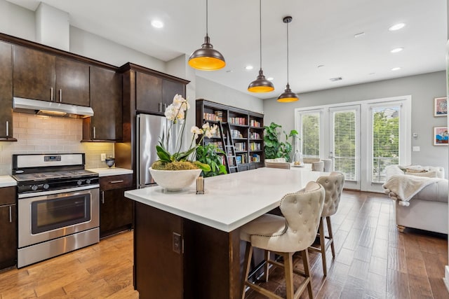 703 Bayou St, Houston, TX 77020 - kitchen featuring stainless steel appliances, under cabinet range hood, light countertops, a kitchen bar, and decorative backsplash