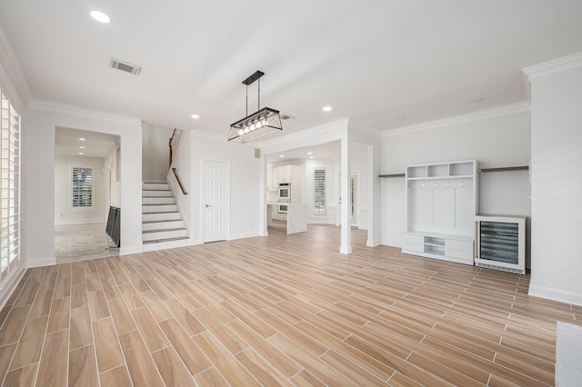 7921 Capri Cir, Houston, TX 77095 - unfurnished living room with wine cooler, stairs, crown molding, light wood finished floors, and recessed lighting