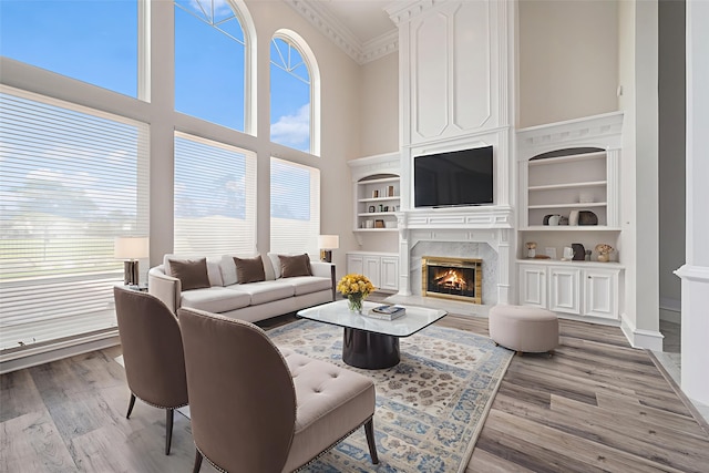 7921 Capri Cir, Houston, TX 77095 - living room featuring a high end fireplace, a towering ceiling, wood finished floors, built in shelves, and crown molding