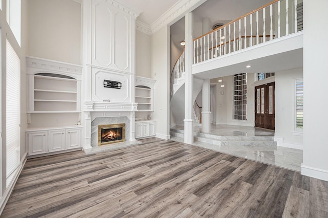 7921 Capri Cir, Houston, TX 77095 - unfurnished living room with a high ceiling, a premium fireplace, stairs, wood finished floors, and healthy amount of natural light