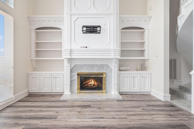 7921 Capri Cir, Houston, TX 77095 - unfurnished living room featuring a premium fireplace, wood finished floors, stairs, and built in features