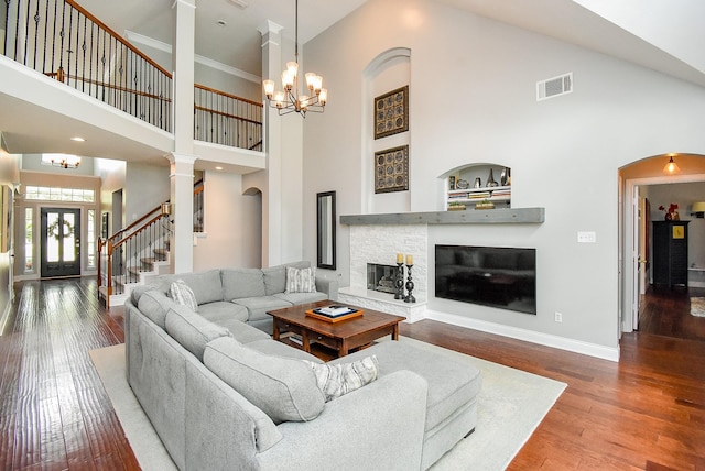 14023 Armant Place Dr, Cypress, TX 77429 - living room featuring a chandelier, a towering ceiling, wood finished floors, a stone fireplace, and arched walkways