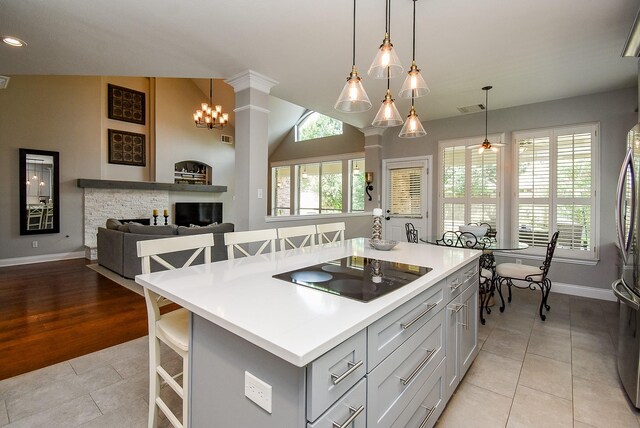14023 Armant Place Dr, Cypress, TX 77429 - kitchen with black electric stovetop, a fireplace, light tile patterned floors, light countertops, and a kitchen breakfast bar