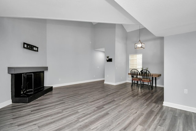 9809 Richmond Ave Unit B13, Houston, TX 77042 - unfurnished living room featuring wood finished floors, a fireplace with raised hearth, high vaulted ceiling, and a chandelier
