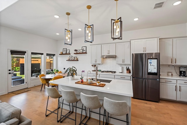 18427 Counce Meadow Ct, Cypress, TX 77433 - kitchen featuring appliances with stainless steel finishes, light wood finished floors, a breakfast bar area, light countertops, and decorative backsplash
