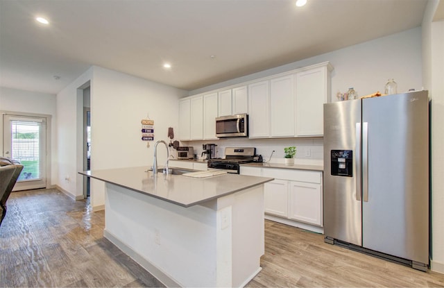 623 Hidden Brook Dr, Baytown, TX 77523 - kitchen with stainless steel appliances, a kitchen island with sink, white cabinetry, light wood-style floors, and recessed lighting