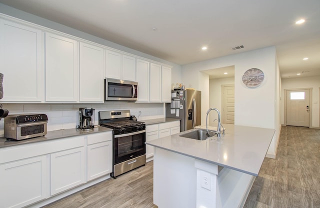 623 Hidden Brook Dr, Baytown, TX 77523 - kitchen featuring appliances with stainless steel finishes, light wood-type flooring, white cabinetry, backsplash, and recessed lighting