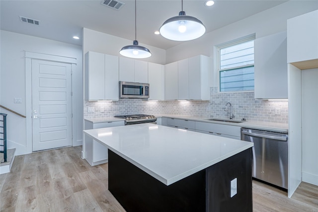 5402 Margarita St, Houston, TX 77020 - kitchen with appliances with stainless steel finishes, light wood-type flooring, light countertops, white cabinets, and hanging light fixtures