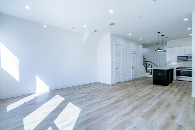 5402 Margarita St, Houston, TX 77020 - kitchen with appliances with stainless steel finishes, recessed lighting, a center island, white cabinets, and light wood-style floors