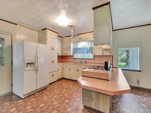 602 Devereaux St, Diboll, TX 75941 - kitchen featuring white refrigerator with ice dispenser, a peninsula, healthy amount of natural light, light countertops, and ornamental molding