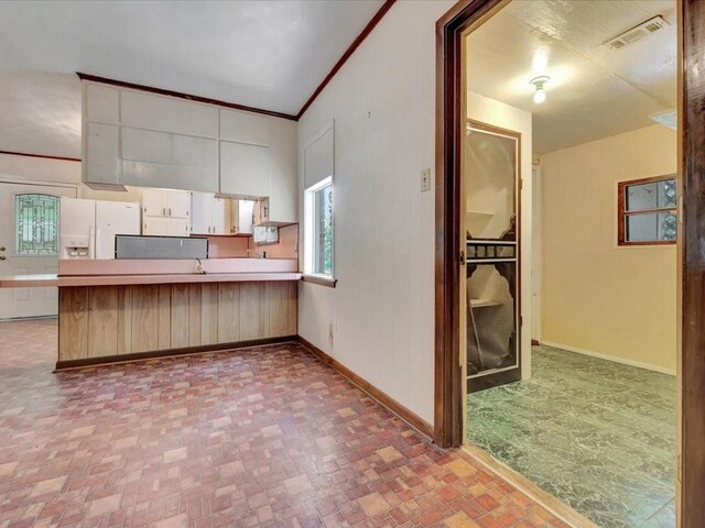 602 Devereaux St, Diboll, TX 75941 - kitchen with a peninsula, white cabinetry, light countertops, and crown molding