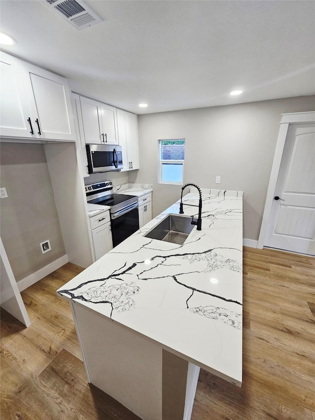 5014 Middleton St, Baytown, TX 77520 - kitchen featuring stainless steel appliances, white cabinets, light wood-style floors, a peninsula, and recessed lighting