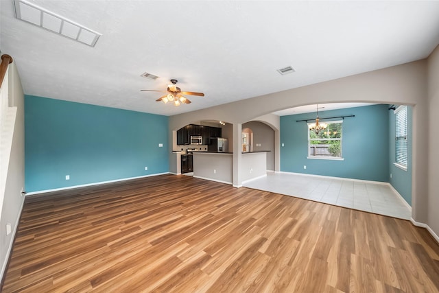 13055 Iris Garden Ln, Houston, TX 77044 - unfurnished living room with light wood-type flooring, arched walkways, ceiling fan, and a chandelier