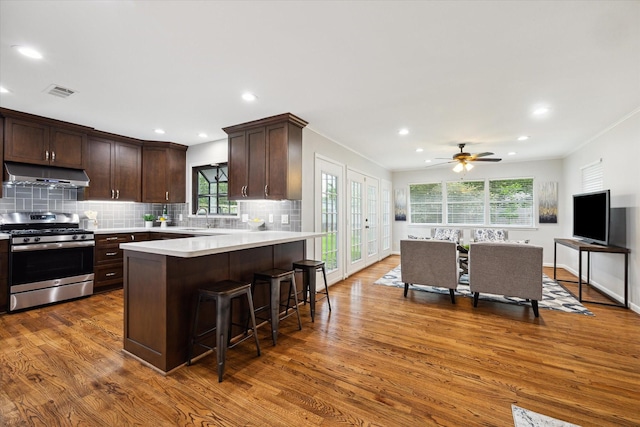 4614 Kinglet St, Houston, TX 77035 - kitchen with stainless steel gas range oven, under cabinet range hood, dark brown cabinets, wood finished floors, and light countertops