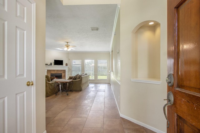 2521 Sea Horse Ct, Seabrook, TX 77586 - entrance foyer featuring a ceiling fan, light tile patterned floors, a textured ceiling, and a fireplace