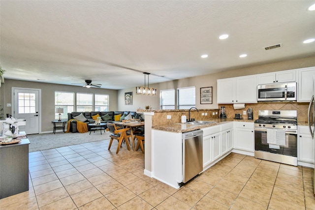 10515 Kentington Oak Dr, Humble, TX 77396 - kitchen featuring stainless steel appliances, a peninsula, recessed lighting, white cabinets, and light tile patterned floors